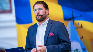Jimmie Åkesson mot bakgrund av en svensk flagga